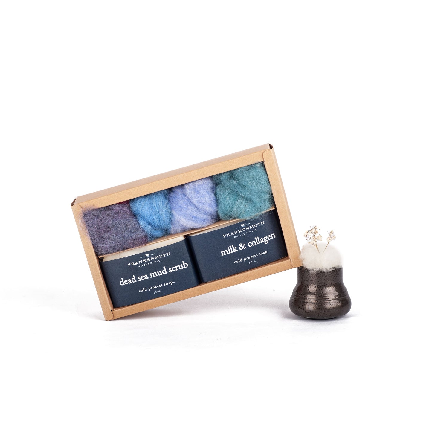 Set of three soaps and wool roving in a box with instructions and a small decorative item on a white background