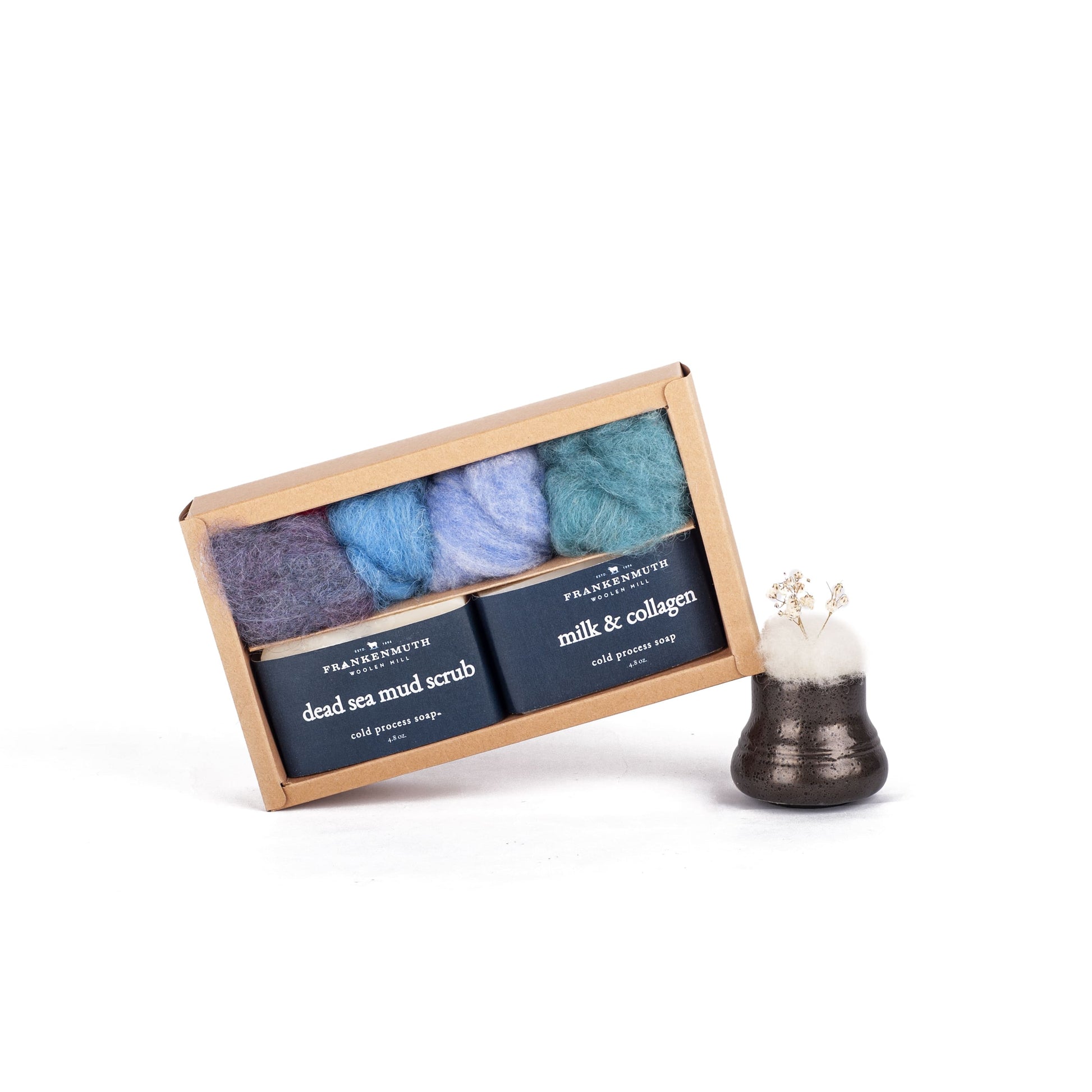 Set of three soaps and wool roving in a box with instructions and a small decorative item on a white background