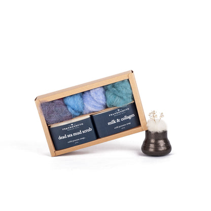 Set of three soaps and wool roving in a box with instructions and a small decorative item on a white background