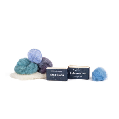 Three bars of soap with wool roving on a white background