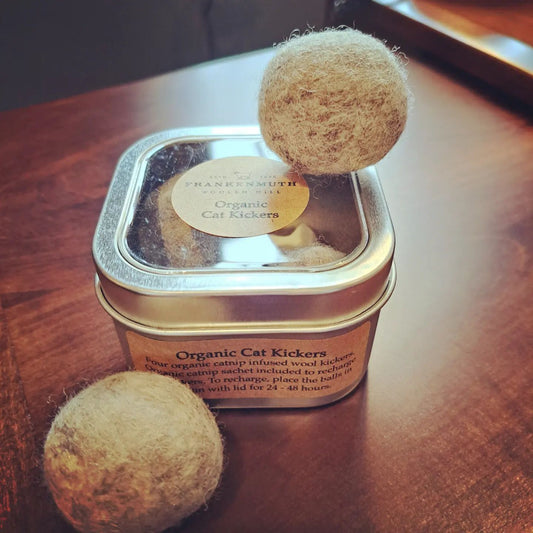 Tin of Organic Cat Kickers with two wool balls on a wooden surface